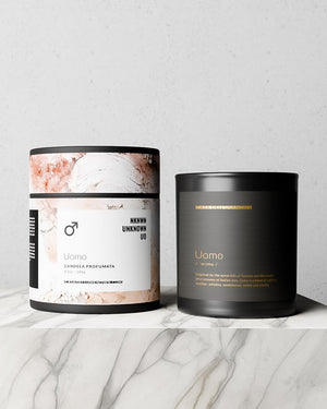 Two candles, one labeled 'Uomo' with a marble design and the other black with gold text, on a marble surface.